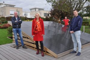 Vier mensen poseren in hun wijk met zonnepanelen die net gelegd zijn.