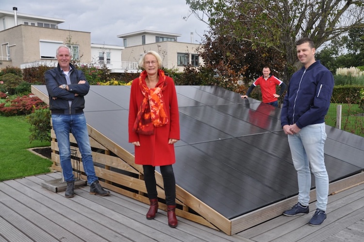 Vier mensen poseren in hun wijk met zonnepanelen die net gelegd zijn.