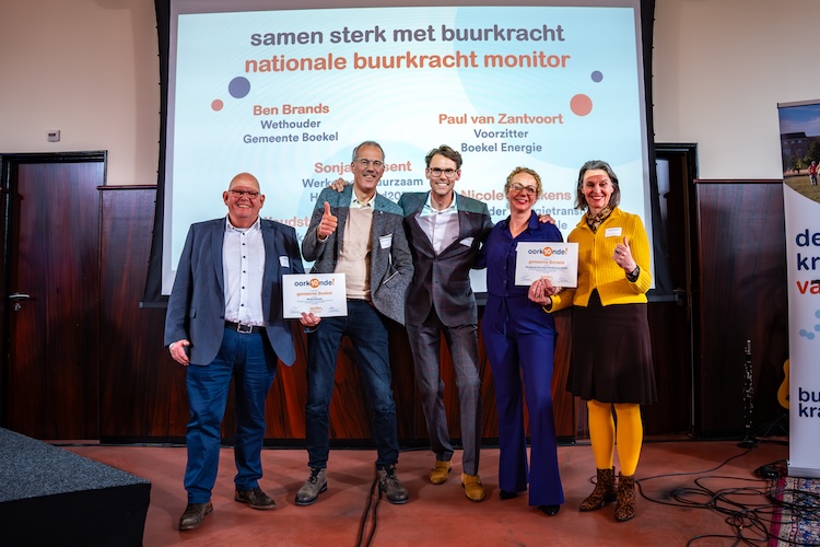 Roel Woudstra poseert met vier mensen voor een groot scherm tijdens de presentatie van de resultaten van De nationale buurkracht monitor 2024.