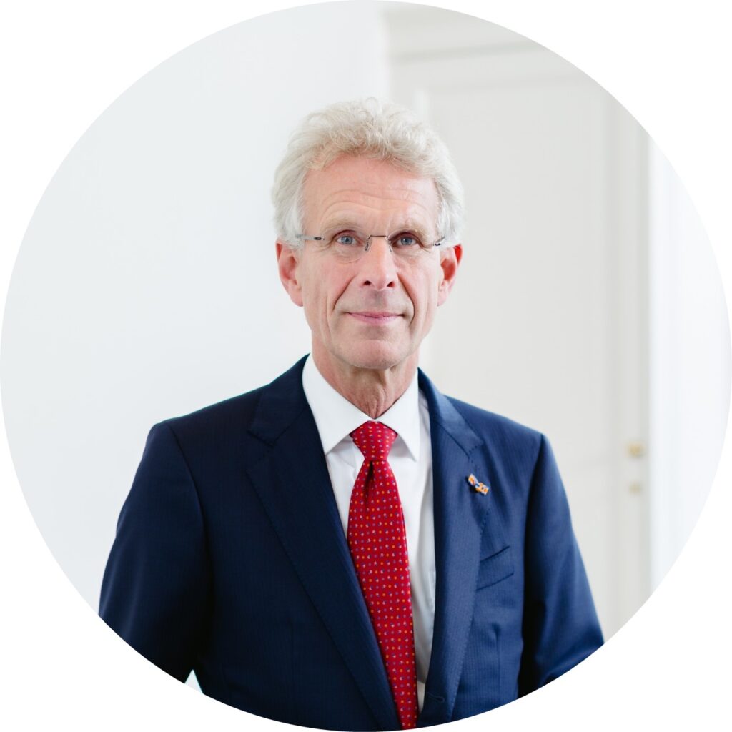 Een portret foto van Ronald, lid van de Raad van Toezicht van Buurkracht, in een donkerblauw pak met rode stropdas voor een witte achtergrond.