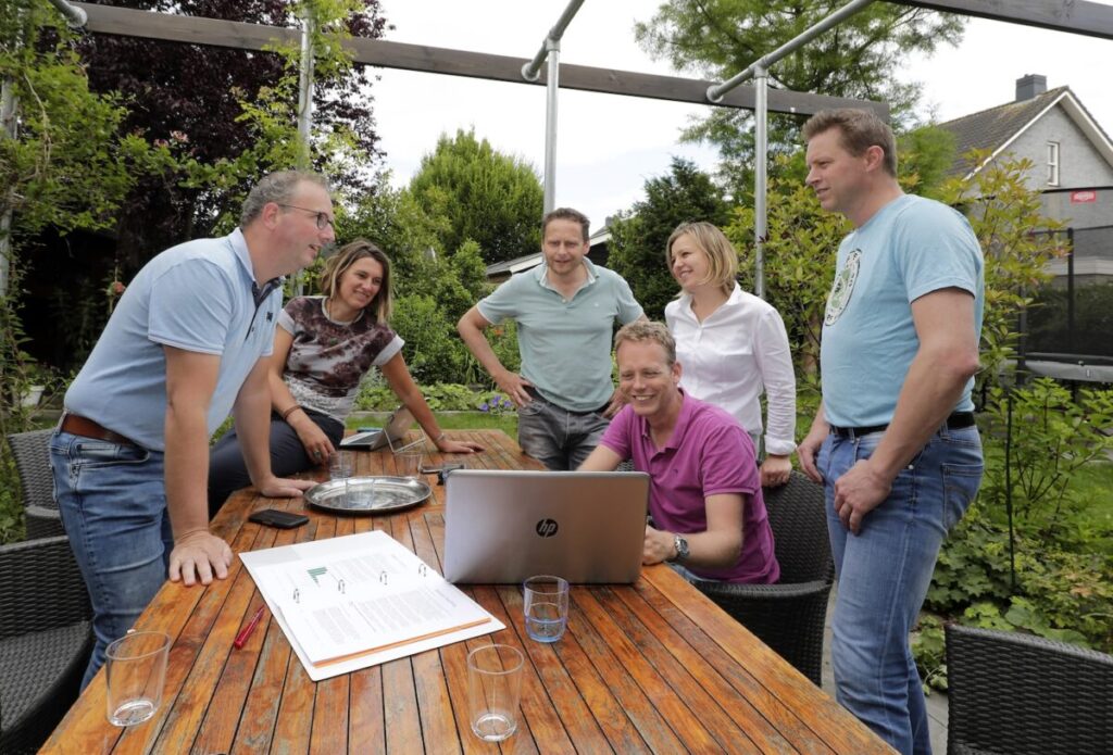 Het buurtteam Berggierslanden staat samen rond een tafel en kijken naar een laptop.