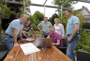 Het buurtteam Berggierslanden staat samen rond een tafel en kijken naar een laptop.